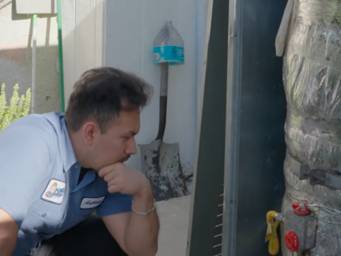 The image shows a Monkey Wrench technician inspecting a tank-style water heater.