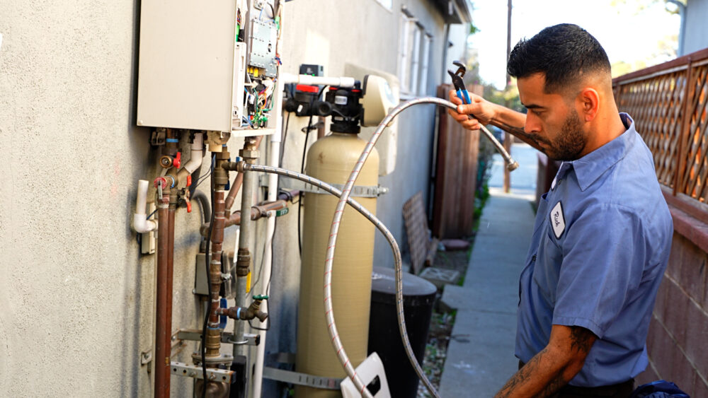 A Monkey Wrench technician grabbing extension lines from a tankless water heater.