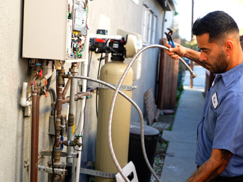 A Monkey Wrench technician grabbing extension lines from a tankless water heater.