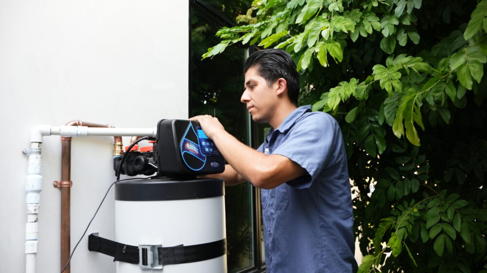 A Monkey Wrench technician is checking a water softener.