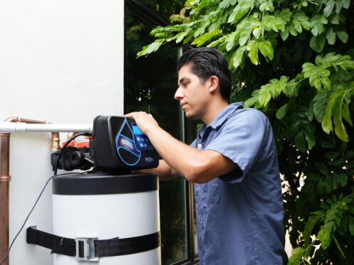 A Monkey Wrench technician is checking a water softener.