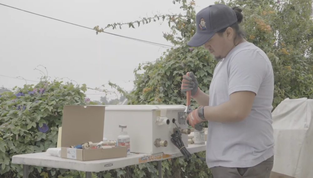 A Monkey Wrench technician preparing a tankless water heater for installation. 