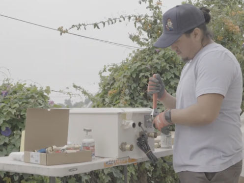 A Monkey Wrench technician preparing a tankless water heater for installation.