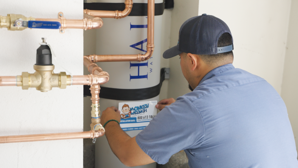 A Monkey Wrench technician placing an install sticker on a whole-house carbon filtration system.