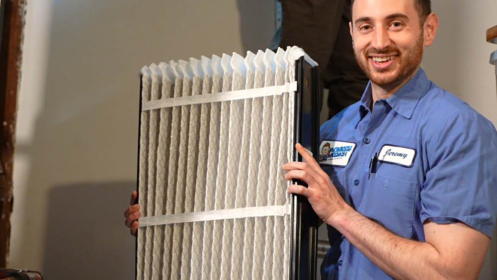 Monkey Wrench technician holding up an HVAC filter.