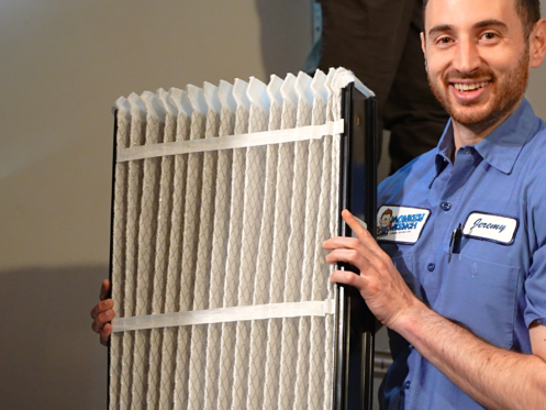 Monkey Wrench technician holding up an HVAC filter.