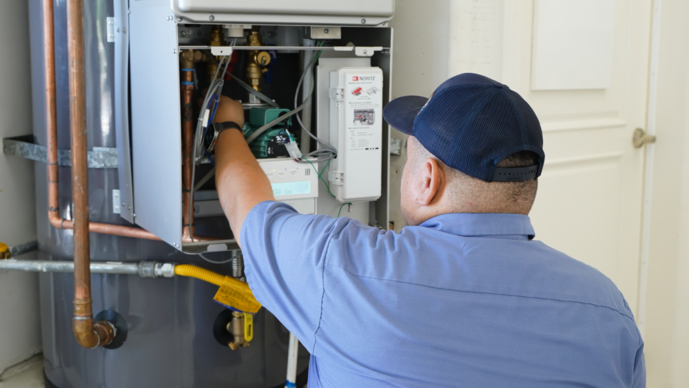 The image shows a Monkey Wrench technician checking the panel of a hybrid hot water heater.