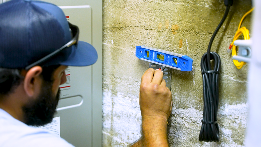 A Monkey Wrench technician is using a level meter to properly size a tankless water heater install. 