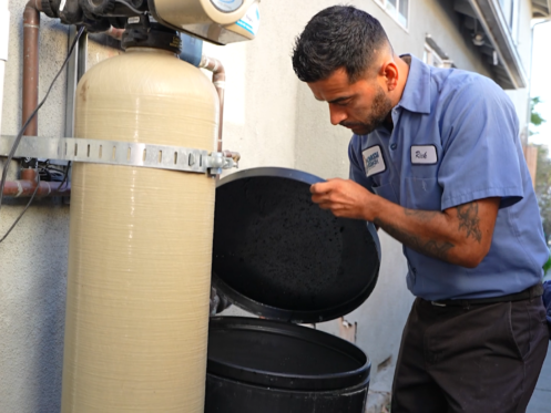 A Monkey Wrench technician is checking the salt levels of a water softener.