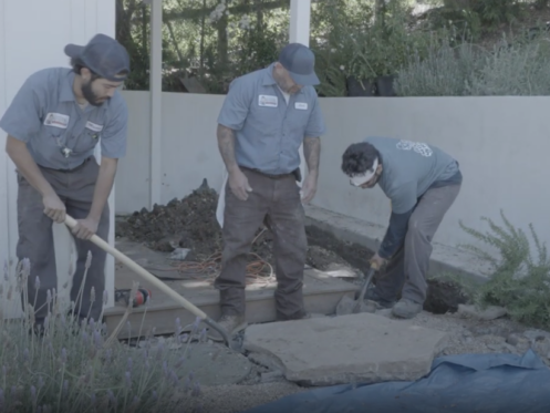 A trio of Monkey Wrench technicians are digging a home's yard to reach the pipes.