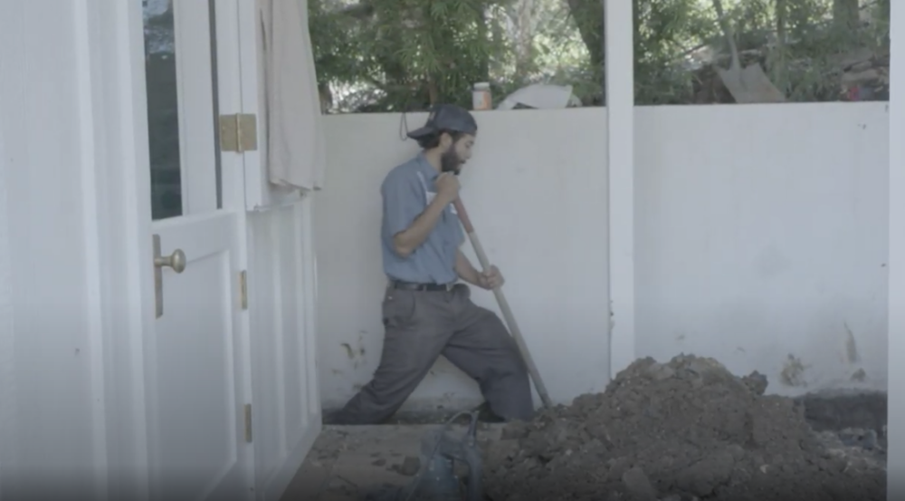 A Monkey Wrench technician using a shovel to dig a trench in a home.