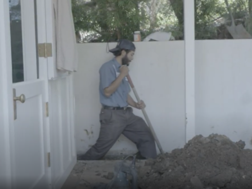 A Monkey Wrench technician using a shovel to dig a trench in a home.