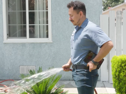 Monkey Wrench technician watering a lawn.