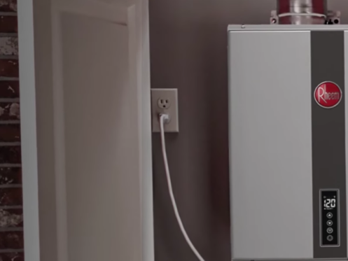 The image shows a Rheem tankless water heater installed inside a home's utility closet.