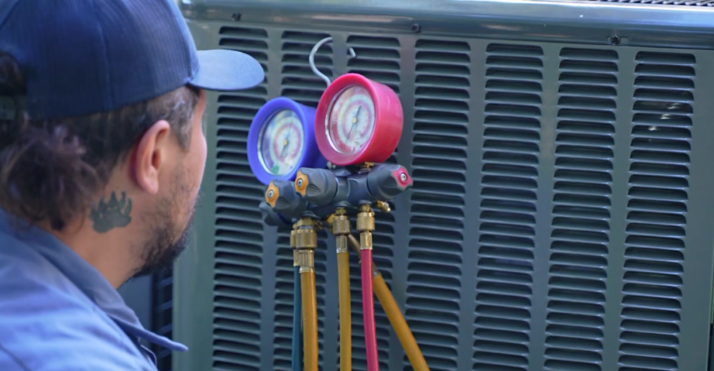 The image shows a Monkey Wrench technician checking the refrigerant levels of a HVAC system.