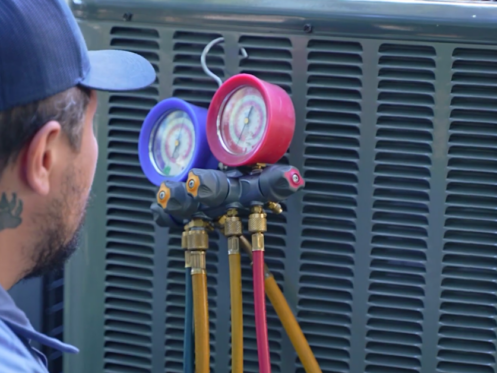 The image shows a Monkey Wrench technician checking the refrigerant levels of a HVAC system.