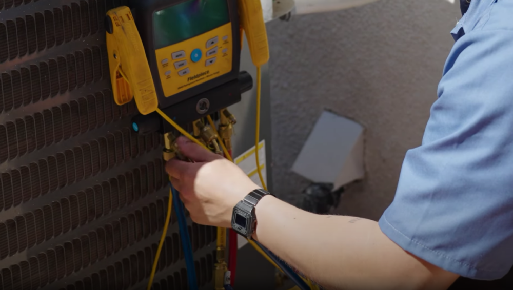 The image shows a technician checking refrigerant levels of an AC unit.