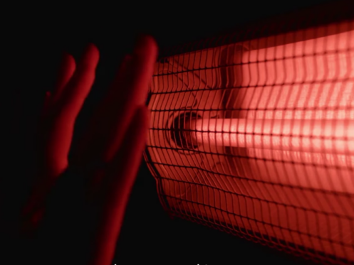 The image shows a hand in front of a heater.