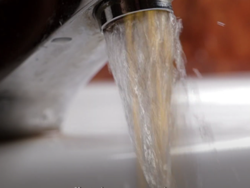 The image shows water running down a faucet.