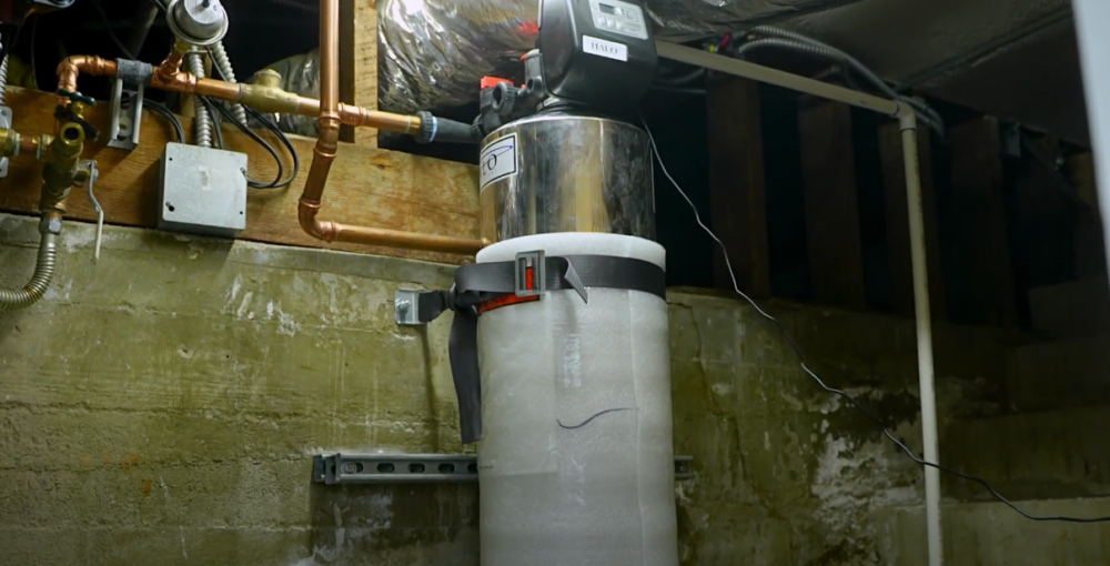 The image shows a water softener installed inside a home. 