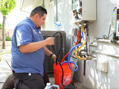 The image shows a Monkey Wrench technician preparing a tankless water heater flush.