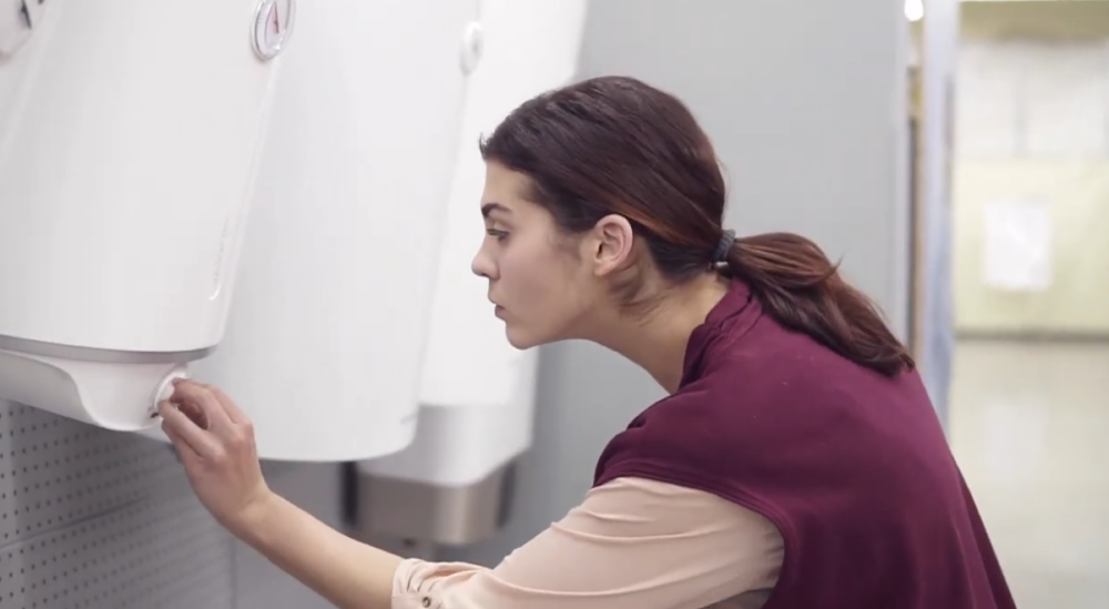 A woman is checking out different tankless water heaters from a store.