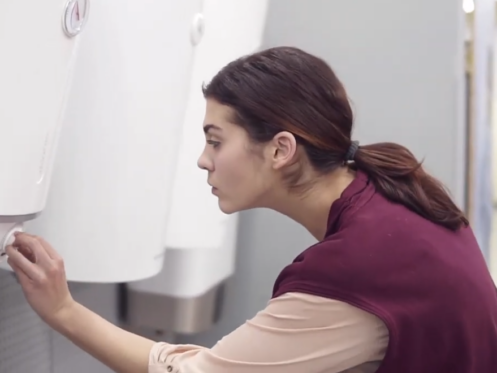 A woman is checking out different tankless water heaters from a store.